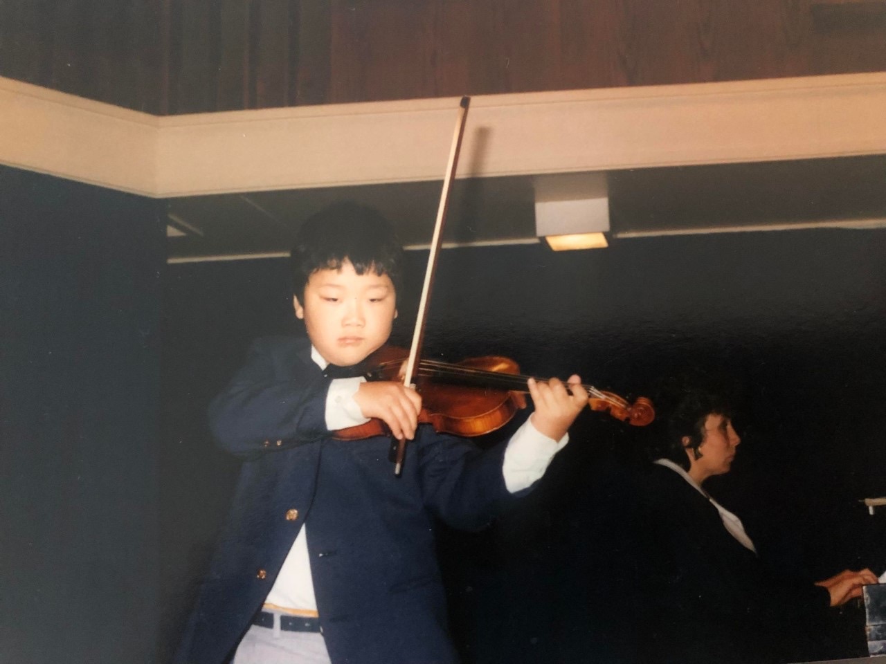 A young Dennis Kim playing the violin at an early recital